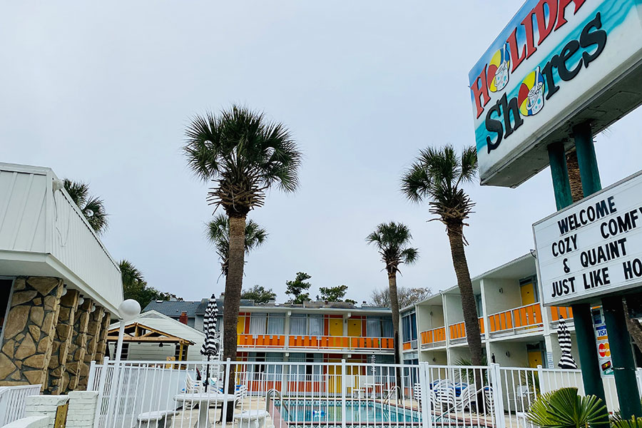 exterior of Holiday Shores with pool area and signage